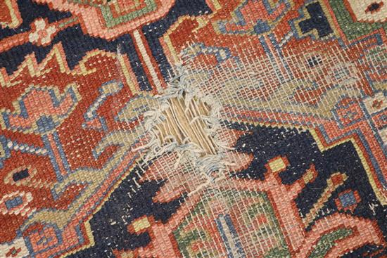A Heriz brick red ground carpet (holed) 325 x 222cm
